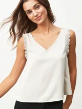 Blusa sin mangas color blanco off-white, con escote en V y detalles de encaje en los tirantes. Diseño holgado y fluido.
