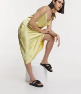 Sandalia plana de color negro con diseño de tiras tubulares acolchadas tipo puffer entrelazadas con nudos. Presenta puntera redonda, plantilla anatómica y suela de goma al tono.