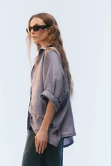 Camisa oversize blanca de lino, con corte cuadrado, mangas raglán cortas con puños anchos, aberturas laterales y cierre frontal de botones.