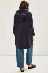 Campera tipo parka de canvas color azul marino, con capucha, cierre frontal y bolsillos laterales. Presenta un bordado en hilo rojo en la parte inferior frontal con la frase 'She's Electric'.