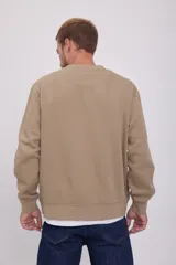 Buzo de cuello redondo y manga larga, corte relajado en color beige. Presenta el logotipo "Originals Studio" estampado en pequeño en el pecho.