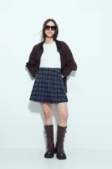 Minifalda tableada con estampado de cuadros en tonos oscuros, de corte acampanado y estilo colegial.
