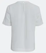 Blusa blanca de poliéster con cuello redondo, mangas cortas, cierre trasero en forma de gota, pequeñas aberturas laterales y acabados en pespuntes en las mangas y el cuello.