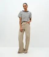 Remera de corte boxy confeccionada en algodón, con diseño de rayas horizontales en blanco y negro, cuello redondo en color negro contrastante y mangas cortas.