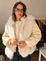 Campera puffer oversize color marrón, con paneles frontales y traseros de pelo sintético suave. Presenta mangas acolchadas, cierre frontal y bolsillo con cierre en la manga.