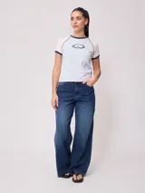 Remera azul marino de algodón con mangas cortas raglán blancas con ribete naranja y estampado ovalado con el logo de Rusty en el pecho.