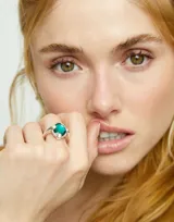 Anillo plateado con un cristal facetado verde en forma de lágrima.