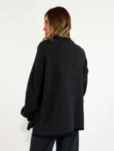 Sweater de tejido de punto en color azul marino, con cuello redondo, mangas largas con puños acanalados y ajuste holgado. Presenta un pequeño aplique decorativo en el ruedo.