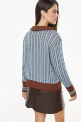 Cardigan de punto con patrón trenzado, color crudo y visón, con cuello solapa, cierre frontal de botones y mangas largas con puños elásticos rayados.