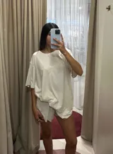 Conjunto de pijama compuesto por un remerón de corte amplio y un short a juego. Presenta un diseño en color beige con detalles de ribetes en color marrón en los bordes. Confeccionado en una mezcla de viscosa, lino y elastano, ofreciendo una caída suave y liviana.