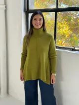 Sweater de punto color verde pistacho, con cuello alto tipo polera, mangas largas y diseño holgado con costuras verticales decorativas.