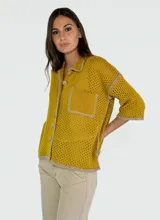 Chaqueta amarilla de tejido calado con cuello camisero, cierre con botones y bolsillo de parche en el pecho.