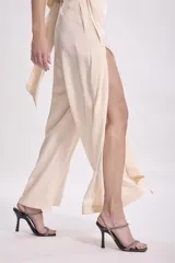 Pantalón negro de tiro alto, corte ancho y fluido, con detalle de cruce o fajín envolvente en la cintura.