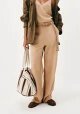 Pantalón recto color beige de tiro medio, con bolsillos laterales y un cinturón fino integrado con detalle de nudos en la parte delantera.