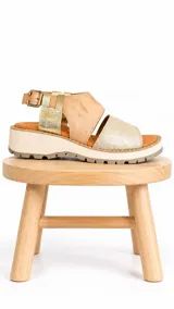 Sandalia de cuero con plataforma track, tiras anchas en tonos beige y camel con detalles metalizados dorados, tira trasera con hebilla metálica ajustable.