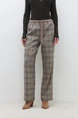 Pantalón largo de corte recto con estampado de cuadros escoceses en tonos beige, marrón y negro. Tiene cintura elástica con cordón ajustable.