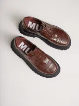 Mocasines color marrón con estampado de cocodrilo y plataforma negra con suela dentada.