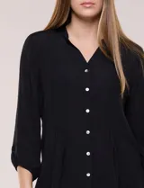 Blusa celeste de silueta suelta y textura liviana, con escote en V, cuello mao y cierre frontal de botones. Cuenta con alforzas verticales en el pecho y mangas tres cuartos con puños elastizados y detalle de galón calado.