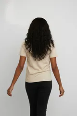 Remera de algodón color beige con estampado floral en tonos azules en el centro del pecho y detalle de texto manuscrito.