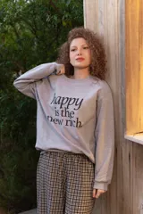 Buzo de cuello redondo gris melange con estampa frontal en negro con la frase "happy is the new rich".