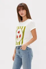 Remera de algodón color beige, de manga corta con vuelta, cuello redondo y estampa frontal de flores con lazo en tonos azules y celestes.
