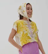 Pañuelo rectangular de tela fina color crema con estampado artesanal de hojas y flores en tonos amarillos y marrones.