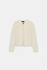 Chaqueta de punto de hilo metalizado color beige con cuello redondo, manga larga y cierre frontal con un botón dorado.