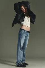 Zueco negro de cuero con punta cuadrada y taco bajo. Presenta una correa con tachas metálicas y una argolla metálica decorativa alrededor del empeine. Cuenta con un recorte en el talón.