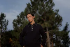 Buzo de punto gris con cuello camisero de denim y cierre frontal parcial con botones metálicos. Presenta mangas largas y un diseño de calce holgado.