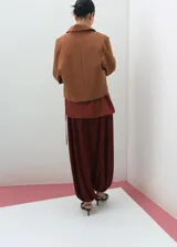 Chaqueta de corte recto color tostado, con cuello camisero, manga larga, dos bolsillos de parche con solapa en el frente y cierre frontal de botones oscuros.