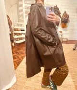 Gabardina marrón de cuero ovino italiano, corte clásico, con cuello camisero y bolsillos laterales.