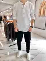 Camisa de muselina blanca de manga larga, con cuello mao y cierre frontal de botones.