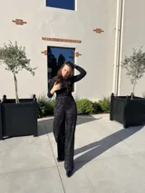 Pantalón negro con lentejuelas plateadas, de corte palazzo y cintura alta.