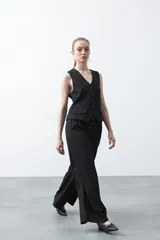 Pantalón wide leg negro de tiro alto con caída fluida y silueta amplia. Presenta cintura alta con botonadura frontal visible.