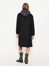 Tapado negro de paño con chaleco interno desmontable con cierre en el cuello. Tiene acceso mediante botones y bolsillos plaque en el delantero.