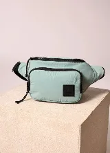 Riñonera Rusty Hachi color verde menta con detalles y cierres negros, bolsillo frontal y parche con logo de la marca.