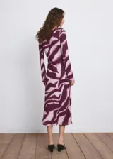 Vestido midi evasé con estampado animal print tipo cebra en tonos bordó y rosado, cuello redondo y manga larga.