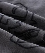Chaqueta de denim color gris con acabado estonado, cierre frontal con cremallera, cuello camisero y manga larga. Presenta un estampado con la palabra 'OUTLAW' en tipografía gótica en el pecho y un bolsillo con cierre en la manga izquierda.
