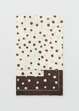 Pañuelo rectangular de tejido fluido con diseño estampado de lunares y terminaciones deshilachadas.