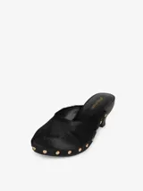 Zueco negro con capellada de pelo de becerro, base de madera con tachas doradas y tacón de cuero.