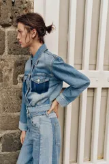 Cazadora corta de denim con cuello solapa y manga larga. Presenta un diseño de lavado combinado a contraste, con bolsillos de plastrón con solapa en el pecho y cierre frontal con botones metálicos.