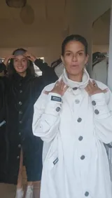 Tapado blanco de diseño holgado con cuello alto envolvente, cierre frontal con botones y mangas largas con detalles en puños.