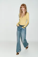 Jeans de tiro alto color azul claro, con cinco bolsillos y pernera recta que se estrecha hacia el tobillo. Incluye un cinturón negro con detalles metálicos. Cierre frontal con cremallera y botón.