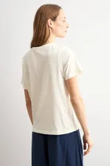 Remera azul marino de manga corta, corte recto y cuello redondo, con detalle de aplicación bordada de flores de crochet en el lateral inferior.