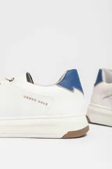 Zapatillas urbanas blancas con detalle azul en el talón y suela de goma.