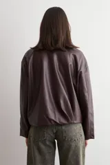Chaqueta bomber de eco cuero en color bordó, con cierre frontal metálico y cuello clásico. Presenta un diseño de corte recto y mangas largas.