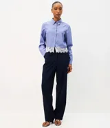 Camisa cropped azul con rayas diplomáticas blancas, cuello clásico, mangas largas y detalle de encaje blanco aplicado en el borde inferior.