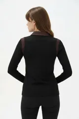 Remera de manga larga al cuerpo confeccionada en lyocell, con diseño color block que combina negro y marrón, cuello tipo camisa y botones frontales.