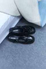 Mocasines negros de cuero vegano con detalle de tachas plateadas en la parte delantera.