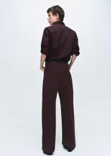 Jeans de tiro bajo y diseño wide leg, confeccionados en tejido de pana color bordó, con cierre de botón y cremallera, trabillas para cinturón y cinco bolsillos.